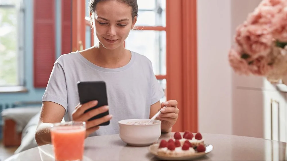 comer con el celular en la mano referencial