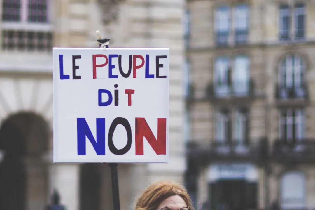 a_woman_holding_a_sign_that_says_le_peuple_dit_non